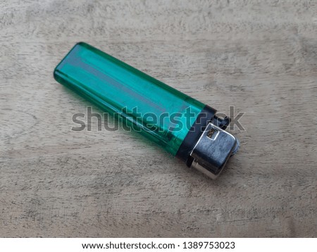 Green plastic gas lighter isolated on wood background