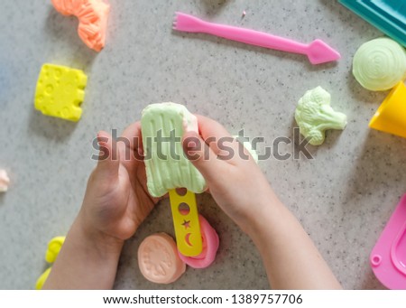 Child's hands with colorful clay. 
ice cream, fruits and vegetables from plasticine. 
Pastel color plasticine. Homemade clay. Close up