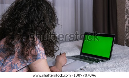 The young woman uses a laptop at home and a cup of tea in the hand. The laptop with green screen