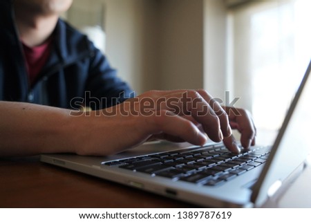 A generic image of hands typing on a laptop computer with natural lighting coming in from the office window. 