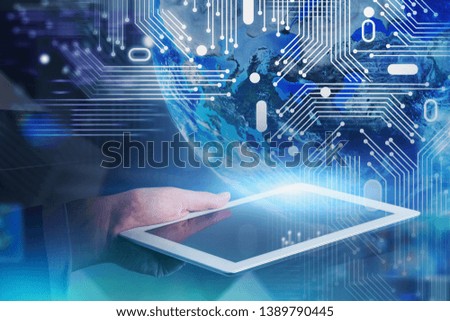 Hand of man holding tablet computer with double exposure of digital Earth hologram. Concept of big data in business. Toned image blurred. Elements of this image furnished by NASA