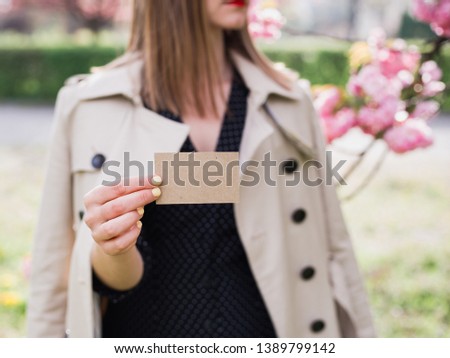 Woman showing business card. Hand holding a craft visit card, gift, ticket, pass, present close up on nature background