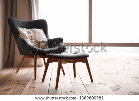 Comfortable armchair and footstool near window in flat Royalty-Free Stock Photo #1389800981