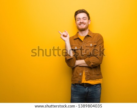 Young redhead man pointing to the side with finger
