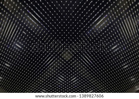Grid, louvered or lath structure of drop ceiling with hidden spot lights. Hi-tech industry or office building interior with mesh pattern. Abstract modern architecture background in black and white.