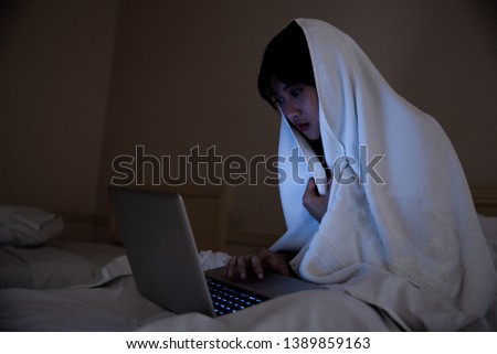 Portrait of girl lying on floor in bedroom at night and using laptop 