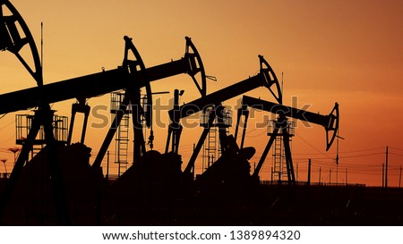 Many oil pumps at sunset under the red sky Royalty-Free Stock Photo #1389894320