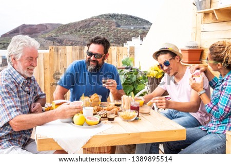 Senior people with family enjoying breakfast together. Three generations. Wooden table and background. Three adult and one teenager.
