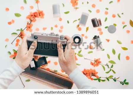 Woman holding vintage camera over springtime floral decoration, spring season is great for starting a new hobby like photography