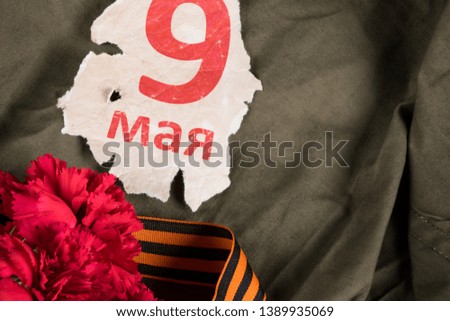 on charred old paper the inscription May 9, next to the red flowers and the St. George ribbon, is the day of the Great Victory