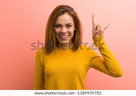 Young pretty young woman showing a horns gesture as a revolution concept.