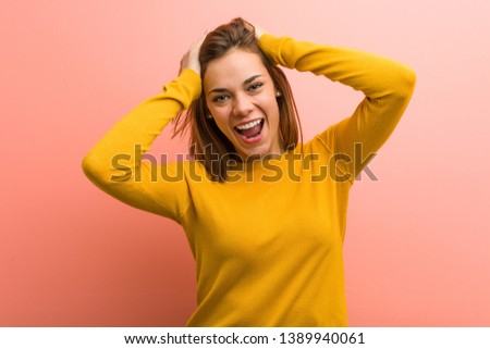 Young pretty young woman laughs joyfully keeping hands on head. Happiness concept.