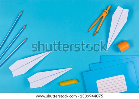 concept of dreams and schooling. Airplanes are hand-made notebooks, school notebooks, watches and school supplies on a blue minimalist background. Flat lay, copy space for your slogan