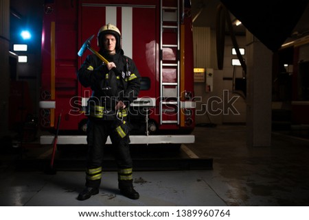 Photo of man fireman with pick on background of fire truck