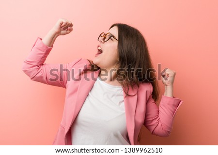Young plus size business caucasian woman raising fist after a victory, winner concept.