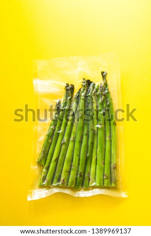 Vacuum sealed vegetables , asparagus, on a yellow background top view, ready to be cooked with sous vide rooner