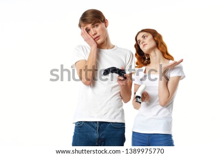 Cute couple in white T-shirts with gamepads in the hands of a video game console