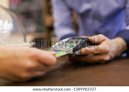 Image of buyer with bank card and seller with terminal in hand