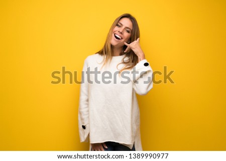 Blonde woman over yellow wall making phone gesture. Call me back sign