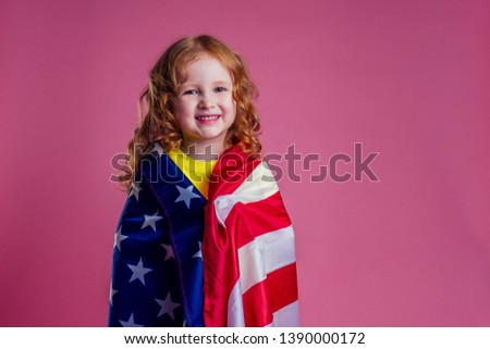 redhead ginger charming female kid celebration independence holding american flag on a pink background in the studio.English language learning concept and freedom dream