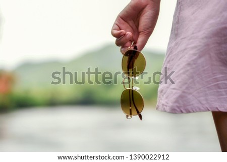 Sunglasses in women hand with blurred background