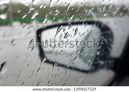 Raindrops on the glass and on the rearview mirror of the car. Dangerous driving in bad weather. Selective focus.