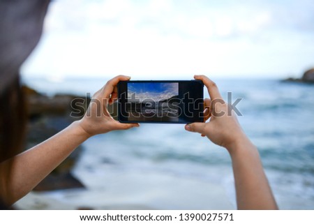 Travelers are taking picture of the sea with a smartphone. Sea images on the smartphone screen.