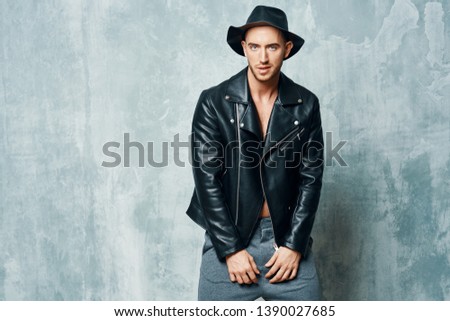 Cute fashionable man in a black leather jacket with a gray hat isolated pattern background