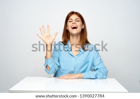 woman in a blue shirt sitting at a desk emotions office work gray background model