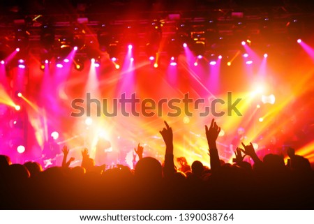 People with their hands up at a concert of their favorite group. Crowd watching a show