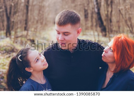 Happy family in autumn park
Overweight man hugging wife and daughter while standing together on alley of autumn park on sunny day