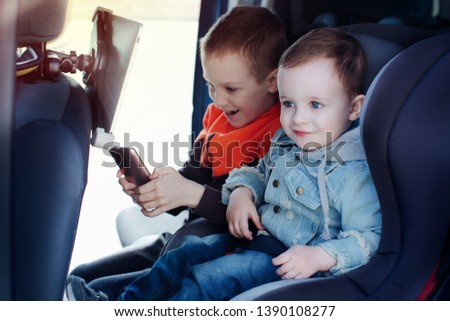 Two children in the car playing mobile phone and tablet. theme of travel, family and children