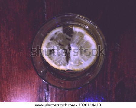 a slice of lemon in a light beer in a glass tumbler, in a dark bar, a bacground picture