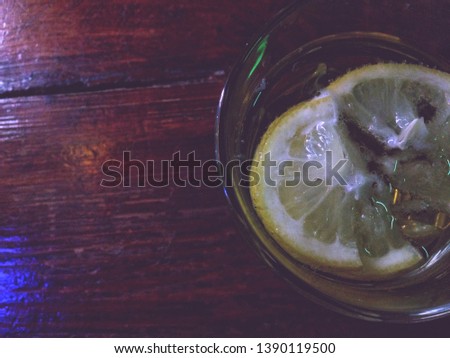 a slice of lemon in a light beer in a glass tumbler, in a dark bar, a bacground picture