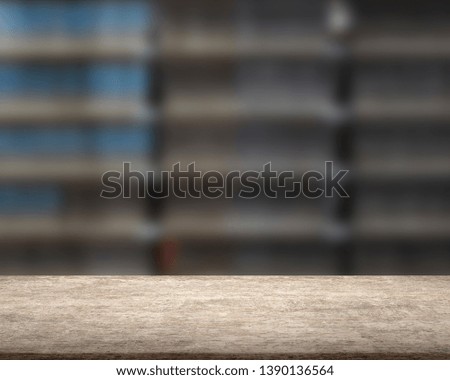 Old brown wooden table with books and bookshelf of blur background, backlight.