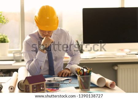 Pensive Architect Think at Engineering Office. Industrial Building Draft Design Concept. Busy Engineer Doubt at Workplace. Business Man Wearing Shirt and Yellow Hard Hat Upset Royalty-Free Stock Photo #1390138727