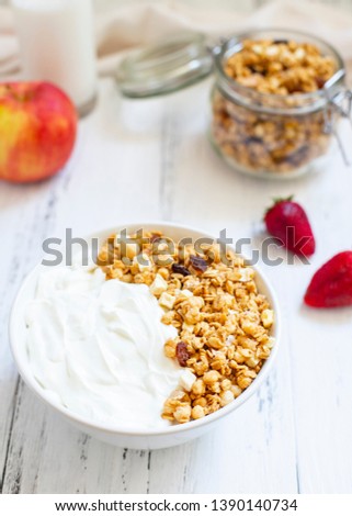 Bowl of Homemade granola with Greek yogurt on a light background. Ingredients for a healthy breakfast - granola, apple strawberry and milk. Close-up