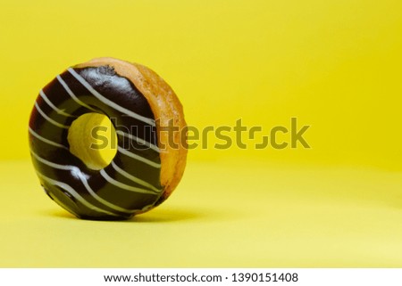 black chocolate donut on yellow background and space for your advertising. retro style background.Collection for celebration design.Sweet dessert