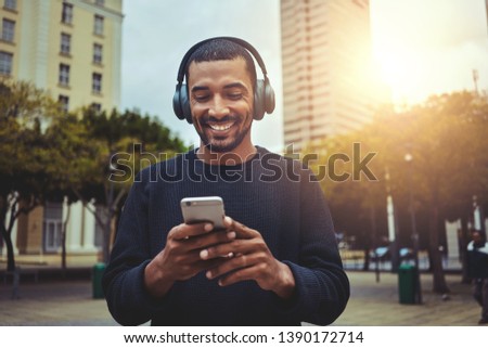 Young man looking at smartphone with headphone on his head Royalty-Free Stock Photo #1390172714