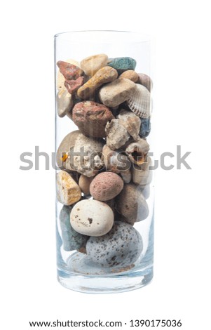 Color pebbles in the glass cup on a white background, isolated