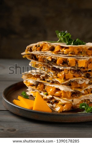 Mexican sandwich - quesadilla with roasted vegetables and cheese. With hot spicy chili sauce served on wooden background.