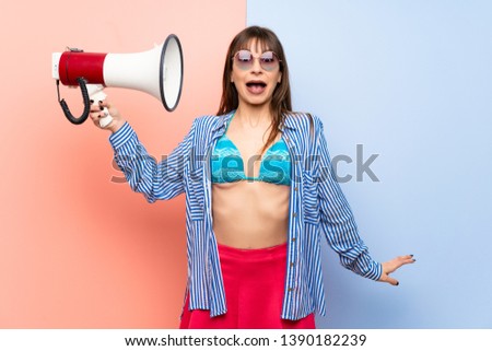 Young woman in bikini taking a megaphone that makes a lot of noise