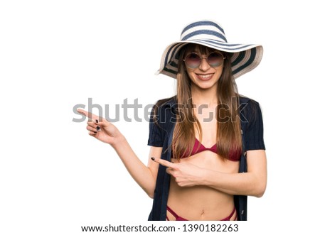 Young woman in bikini pointing finger to the side over isolated white background