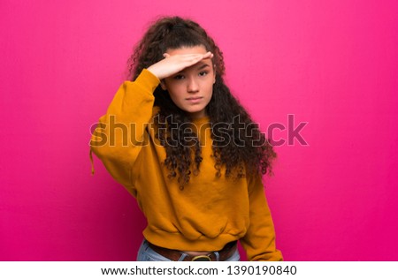 Teenager girl over pink wall looking far away with hand to look something