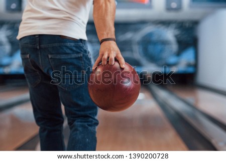 This is gonna be the strike. Rear particle view of man in casual clothes playing bowling in the club.