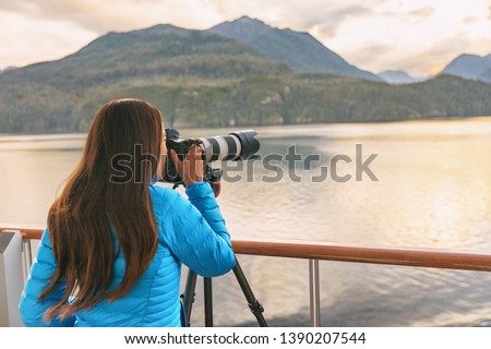 Travel photographer with professional telephoto lens camera on tripod shooting wildlife in Alaska, USA. Scenic cruising inside passage cruise tourist vacation adventure. Woman taking photo picture.