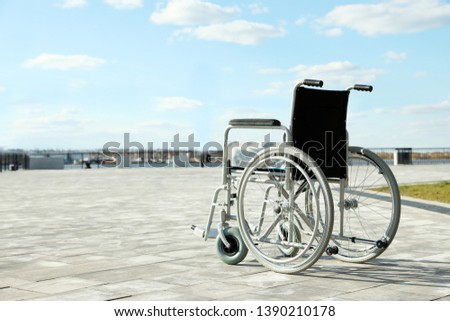 Empty wheelchair outdoors on sunny day. Space for text