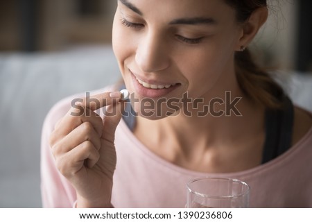 Close up face of healthy attractive woman holding pill and glass of water everyday taking omega 3, probiotics, multivitamin vitamin complex and supplements for beauty skin and body health care concept Royalty-Free Stock Photo #1390236806