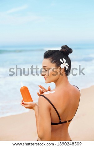 Beautiful Woman in Bikini Applying Sun Cream on Tanned  Shoulder. Sun Protection. Skin and Body Care. Girl Using Sunscreen to Skin. Portrait Of Female Holding Suntan Lotion and Moisturizing Sunblock.