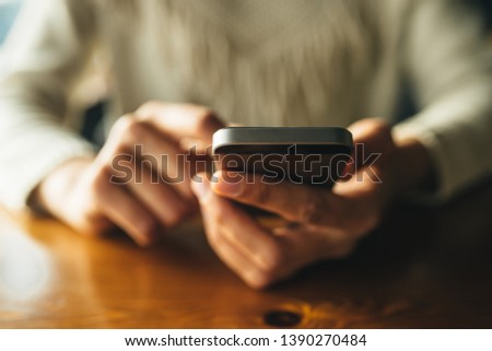 Woman using smartphone on wooden table in cafe. Close-up image with social networks concept